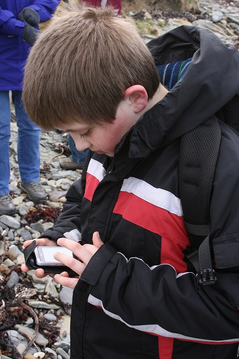A boy using a smartphone to record an eroding archaeological site