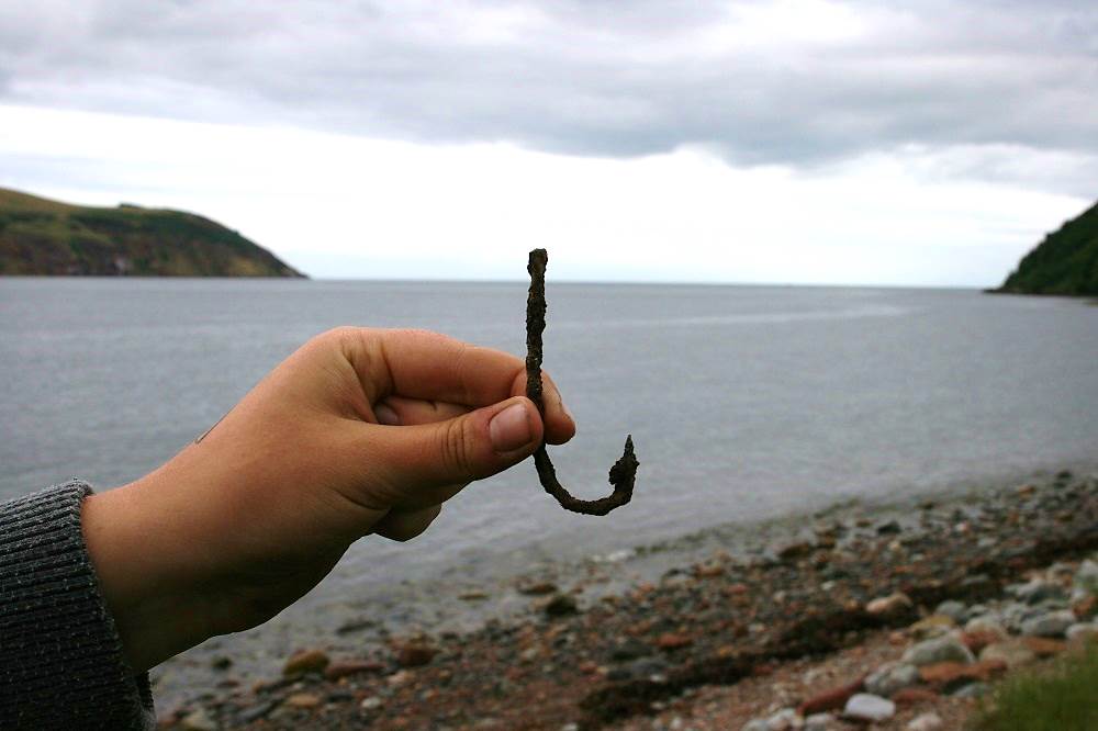 Sophie holding her star find: a medieval fish hook recovered from the shell middens exposed in the eroding coast edge.