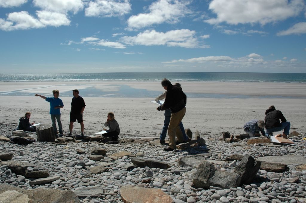 A group of people standing on a beach with tape measures and clipboards
