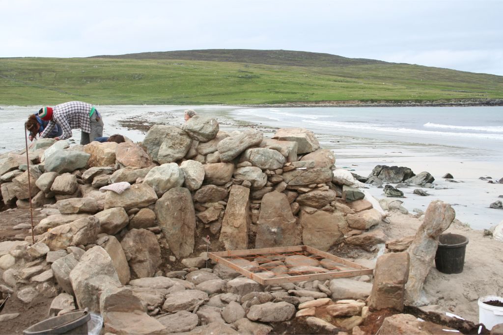 A structure on a beach built of drystone walls faced with upright stone slabs