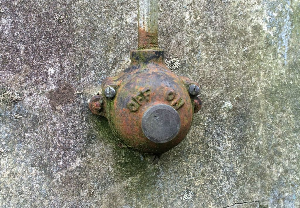 An old-fashioned metal light switch on a concrete wall, with 'off' and 'on' labels
