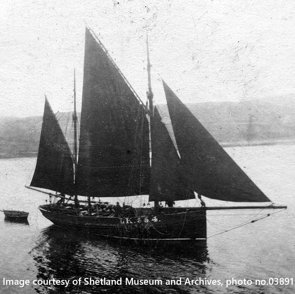 Old black and white photograph of a large wooden fishing boat under sail