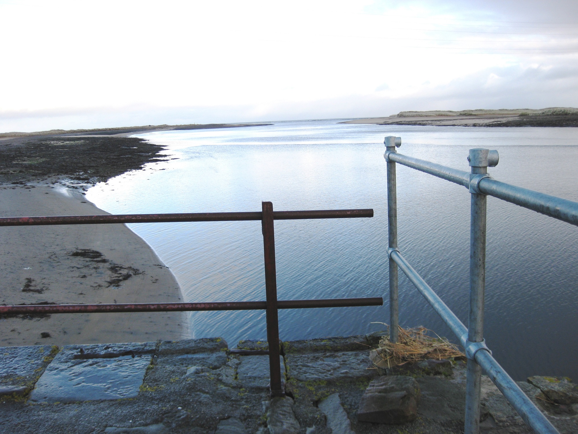 Old and new railings with erosion at bottom right hand corner.   Photo taken facing east this is Loch Fleet's exit to the sea.