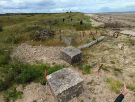 End of east section of line of anti-tank blocks in dunes at edge of golf course. Anti glider posts in the intertidal zone in the background.