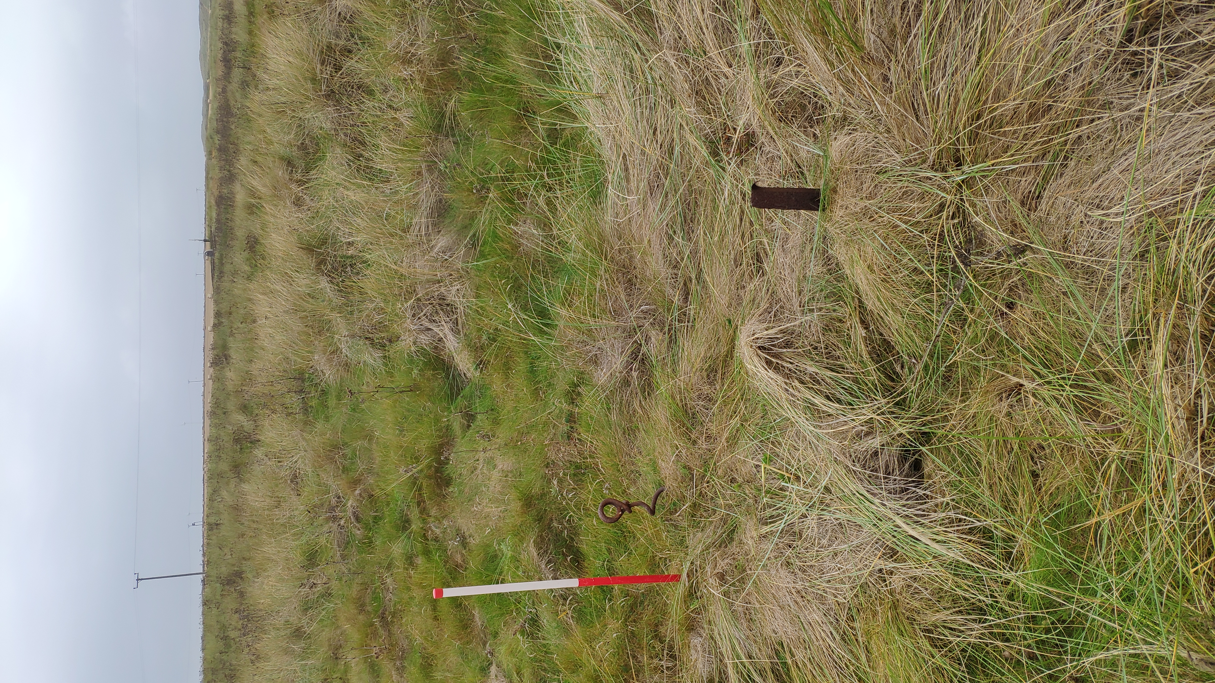 Tripod leg and securing pegin foreground, rocket pole just visible in background behind memorial