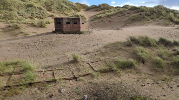 Remains of scaffolding strip in relation to pillbox within Foveran Links, looking east