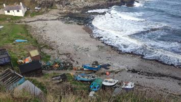 General view of harbour. Old pier visible partially submerged in the middle of the bay. Railed slipway in background in front of the landrover. Current slipway in foreground.